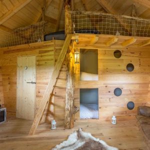 Cabane en bois avec mezzanine, décor chaleureux et ambiance naturelle.
