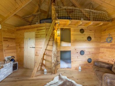 Cabane en bois avec mezzanine, décor chaleureux et ambiance naturelle.