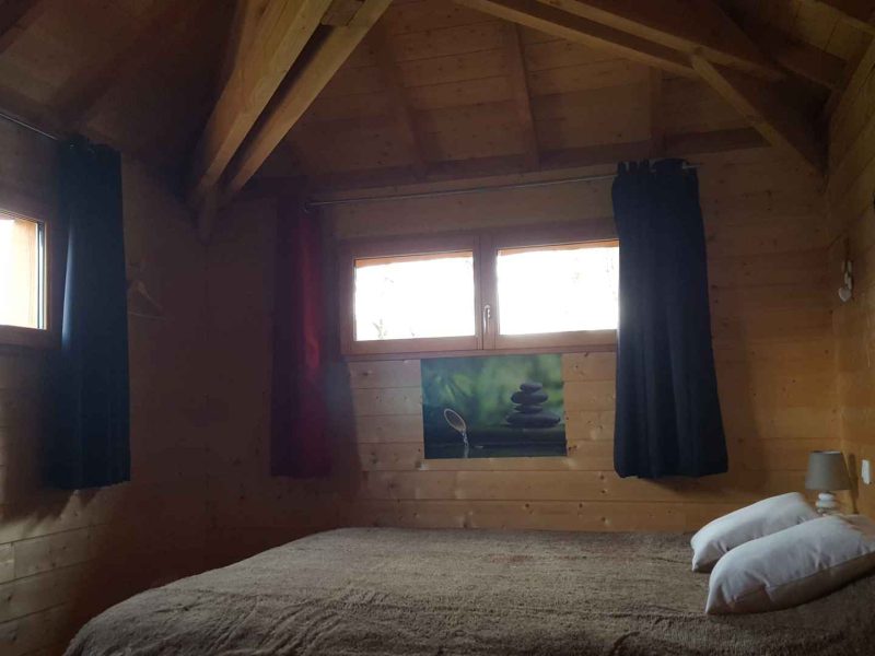 Chalet en bois chaleureux avec lit double et vue sur la nature.