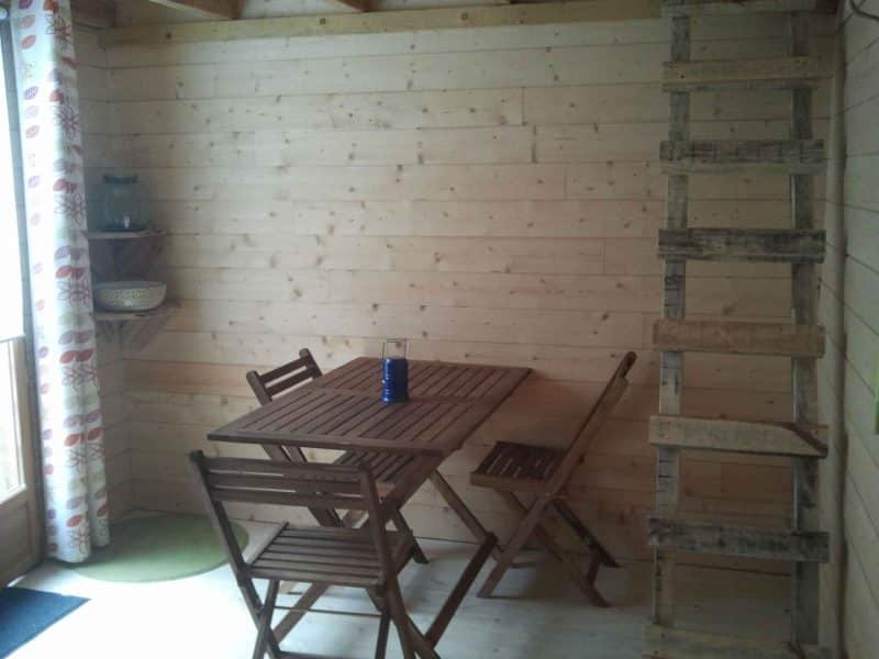 Chalet en bois chaleureux avec table en bois et échelle menant à une mezzanine.