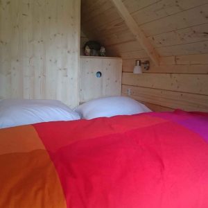 Chalet en bois chaleureux avec un lit coloré et des murs en bois naturel.