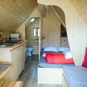 Cabane en bois cosy avec lit douillet et cuisine intégrée. Parfait pour un séjour insolite.