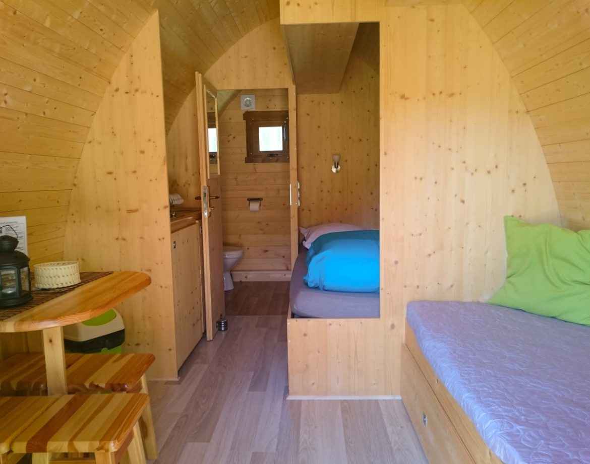 Hébergement insolite en bois, intérieur chaleureux avec lit et coin repas.