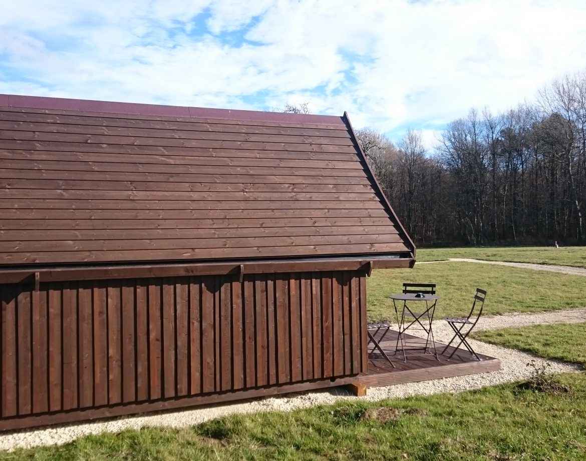 Cabane en bois avec terrasse, entourée de verdure et de forêt au Centre.