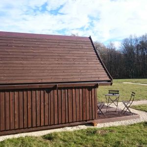 Cabane en bois avec terrasse, entourée de verdure et de forêt au Centre.