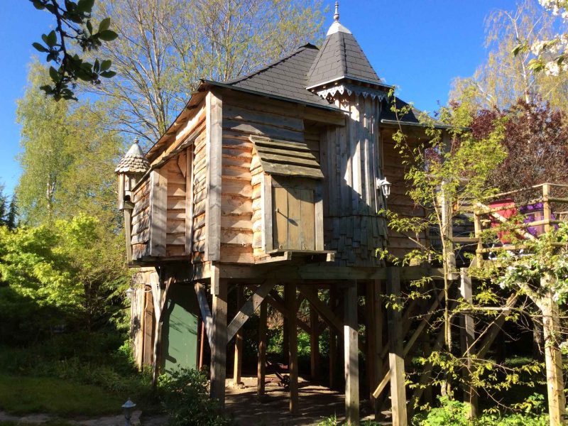 Cabane dans les arbres en bois, perchée au milieu dune verdure luxuriante.