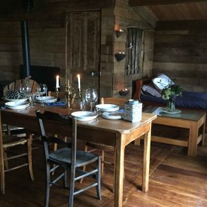 Hébergement insolite en Limousin : chalet en bois avec table à manger et lit cosy.