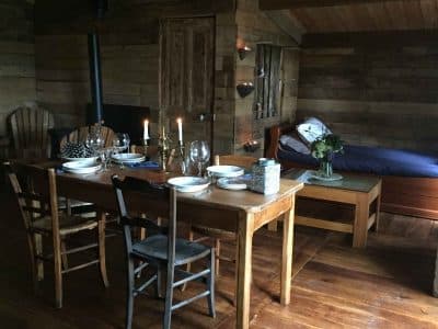 Hébergement insolite en Limousin : chalet en bois avec table à manger et lit cosy.