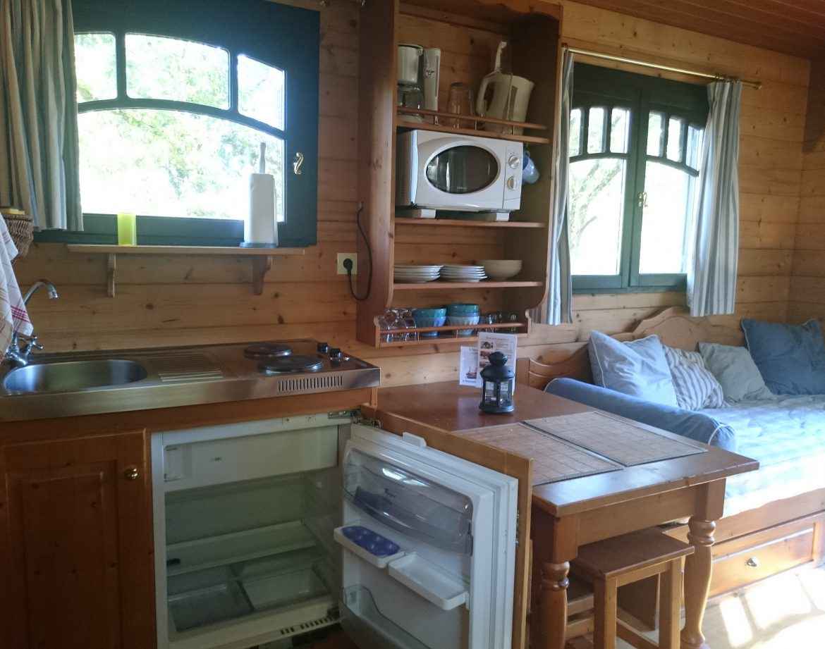 Cabane en bois avec cuisine équipée et lumière naturelle, idéale pour un séjour unique.