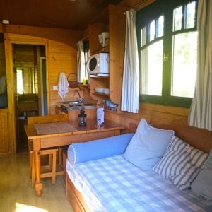 Cabane en bois cosy avec cuisine équipée et coin salon lumineux.