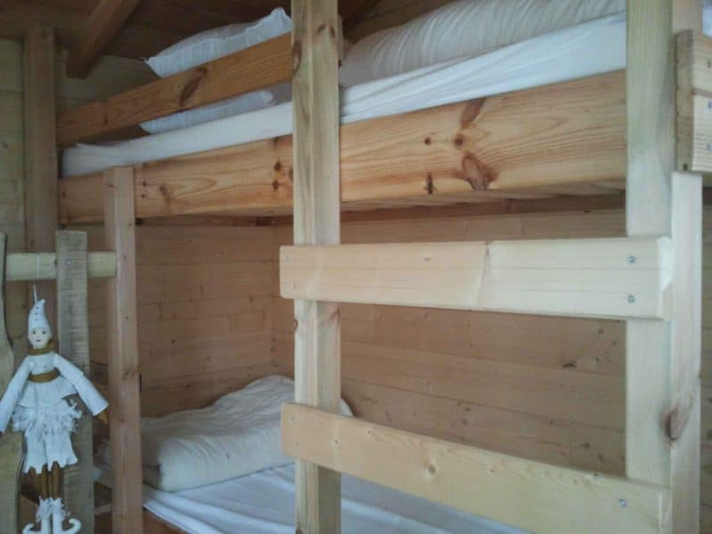 Chalet en bois avec lits superposés, ambiance chaleureuse et décor rustique.