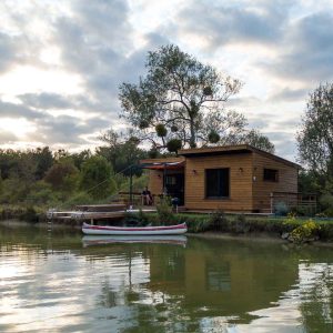 Cabane sur leau en Aquitaine, entourée de verdure et reflet dans leau.