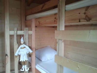 Cabane en bois avec lits superposés et une poupée en bois décorative.
