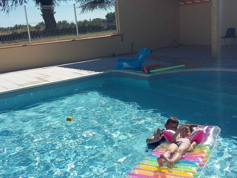 Villa avec piscine, enfants se relaxant sur un matelas flottant coloré.