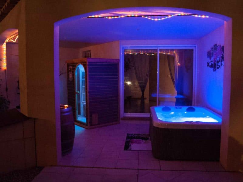 Hébergement de luxe avec jacuzzi illuminé et sauna, ambiance relaxante.