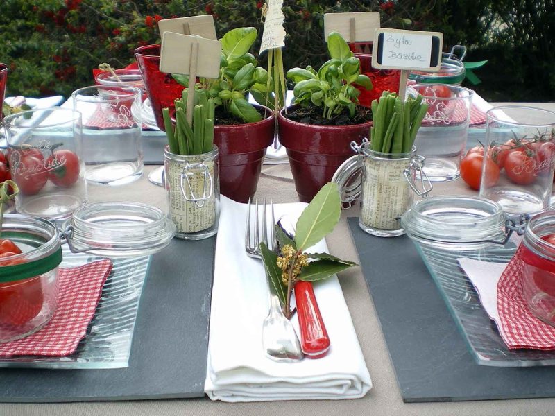 Table élégamment dressée avec des pots de plantes et des tomates cerises, idéale pour un séjour.