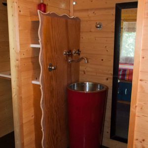 Cabane en bois avec lavabo design rouge et intérieur chaleureux en Provence-Alpes-Côte dAzur.