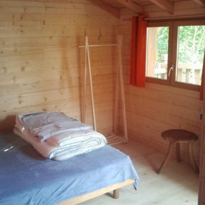 Chalet en bois chaleureux avec lit douillet et fenêtre lumineuse en Aquitaine.