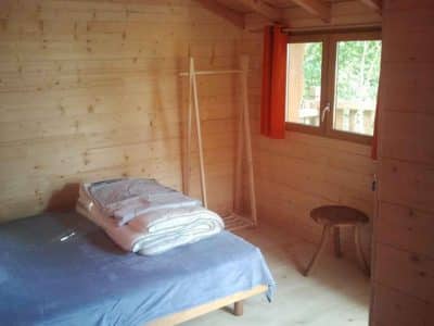 Chalet en bois chaleureux avec lit douillet et fenêtre lumineuse en Aquitaine.