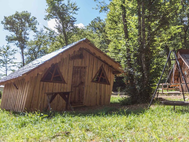 Cabane en bois atypique en Alsace, entourée de verdure et darbres.