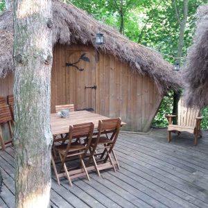 Cabane perchée en Bourgogne, avec terrasse en bois et toit en chaume.