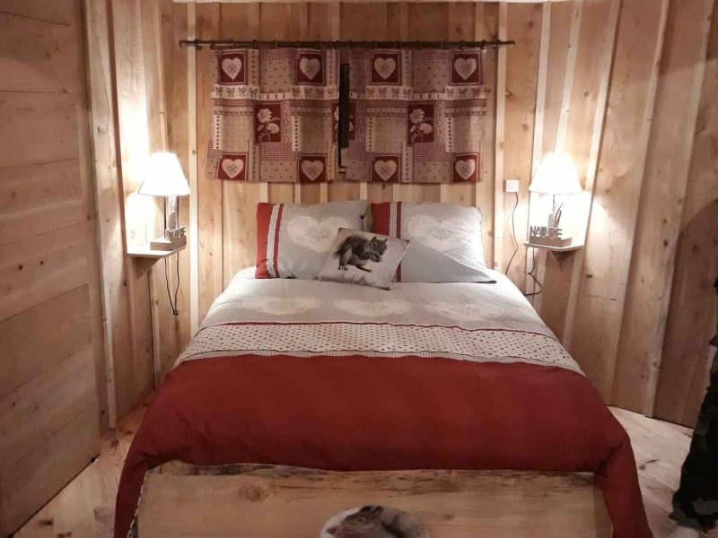 Chalet en bois chaleureux avec lit douillet et décoration rustique en Auvergne-Rhône-Alpes.