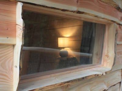Cabane en bois avec une fenêtre révélant une lampe chaleureuse à lintérieur.