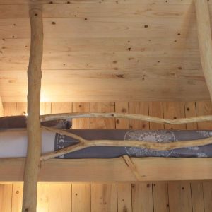 Cabane en bois avec lit en mezzanine et décor naturel chaleureux.