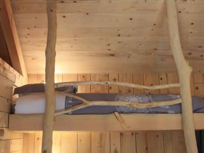Cabane en bois avec lit en mezzanine et décor naturel chaleureux.