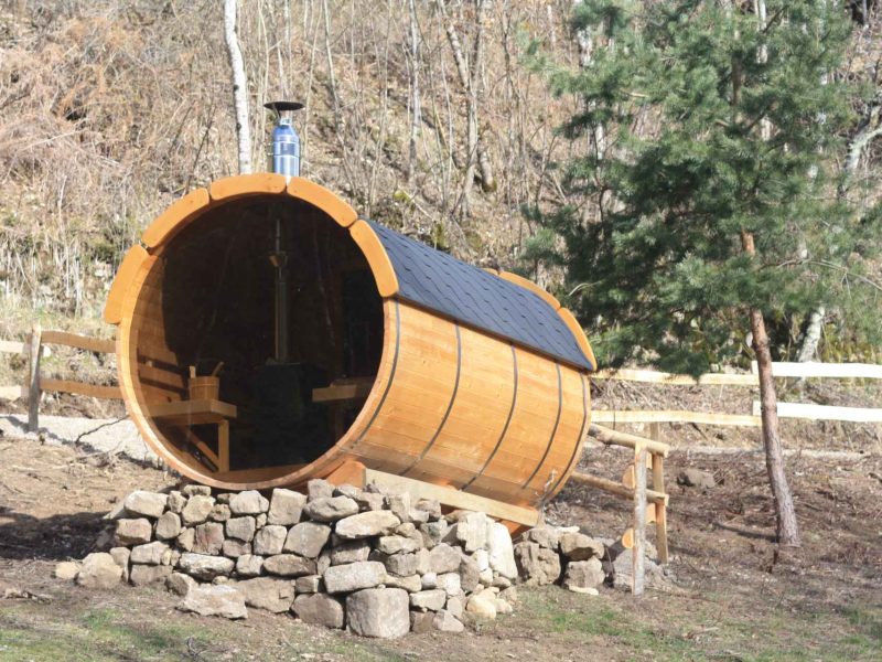Hébergement insolite : un chalet en forme de tonneau, entouré de nature verdoyante.