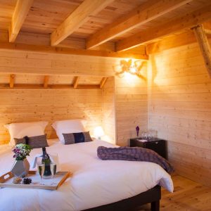 Chalet en bois chaleureux avec lit douillet et décoration en bois naturel.