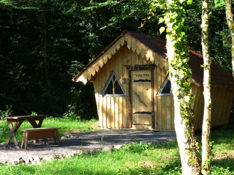 Cabane en bois en Alsace, avec toit en pente et fenêtres en forme de triangle.