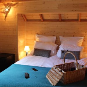 Chalet en bois chaleureux avec lit douillet et panier en osier décoratif.