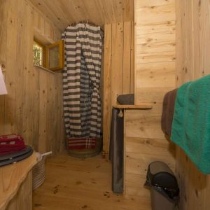 Cabane en bois chaleureuse avec douche et décoration en bois naturel.
