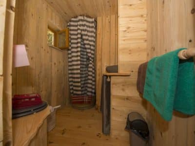 Cabane en bois chaleureuse avec douche et décoration en bois naturel.