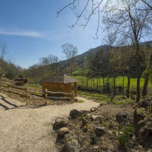 Cabane en bois au cœur de la nature, entourée de verdure et de collines.