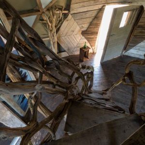 Cabane perchée en bois dans le Grand-Est, avec un escalier en branches sculptées.