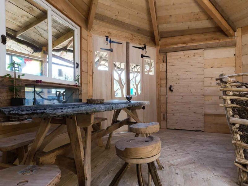 Cabane en bois avec une table en pierre et des bancs en rondins. Ambiance chaleureuse.