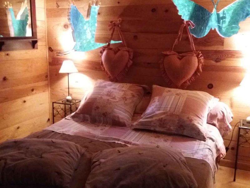 Chalet en bois chaleureux avec lit douillet et décorations murales en forme de papillons.
