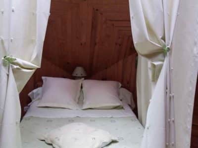 Chambre cocooning en bois, drapée de rideaux, au cœur de la Nouvelle-Aquitaine.