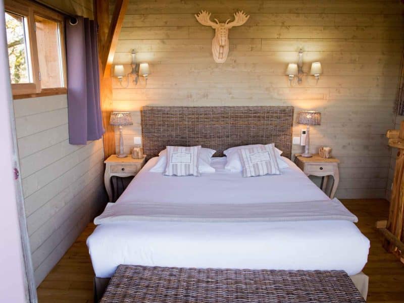 Chalet en bois avec lit douillet et décoration chaleureuse. Ambiance cosy et accueillante.