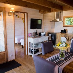 Hébergement insolite en Midi-Pyrénées : chalet en bois avec cuisine moderne et vue sur la nature.
