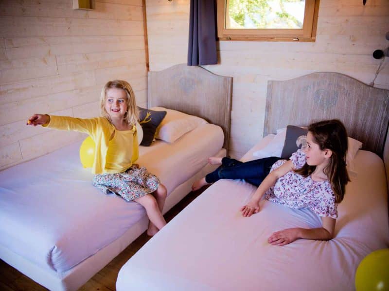 Chalet familial lumineux avec deux lits simples et des enfants joyeux.