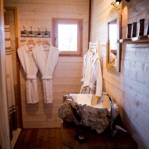 Salle de bain en bois avec peignoirs, dans un hébergement insolite en Midi-Pyrénées.