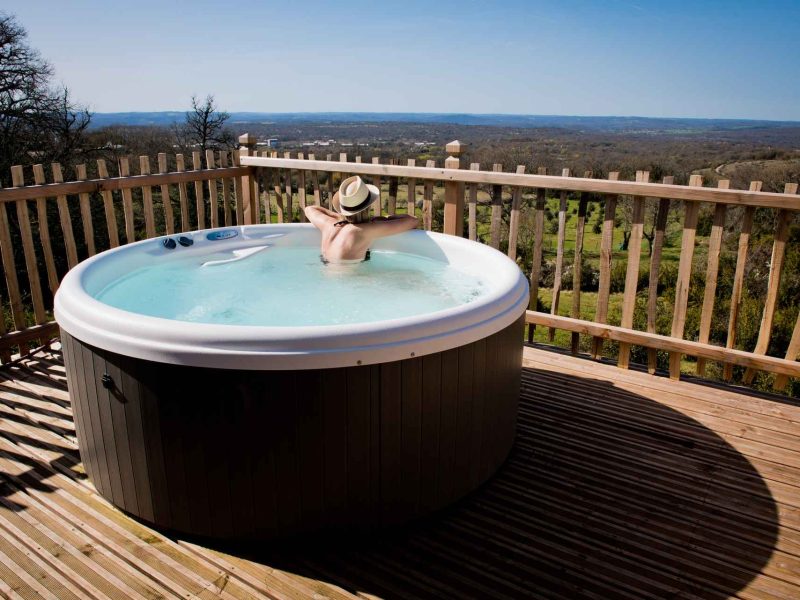 Hébergement en chalet avec jacuzzi sur terrasse, vue panoramique sur la nature.