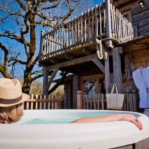 Cabane perchée en bois avec jacuzzi, vue sur la nature en Midi-Pyrénées.