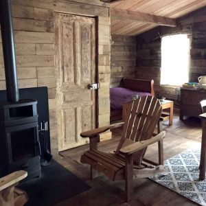Cabane en bois dans le Limousin, avec un poêle à bois et des fauteuils confortables.
