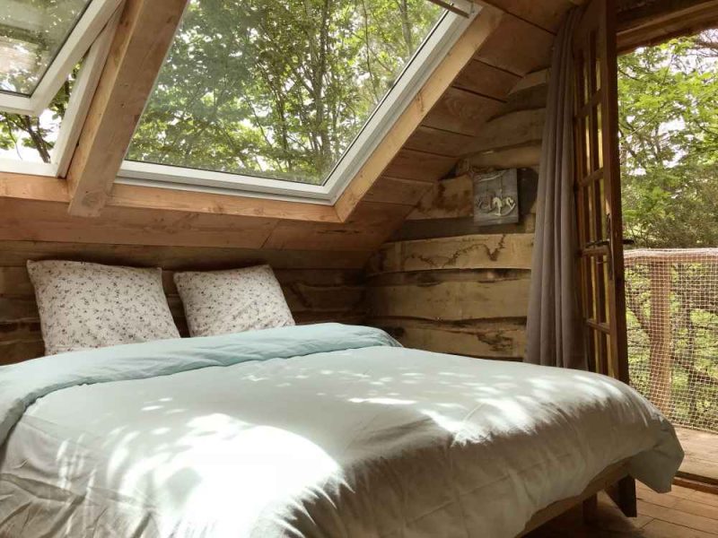 Cabane en bois à Limousin, avec un lit confortable et de grandes fenêtres.