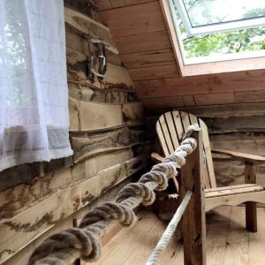 Cabane en bois dans le Limousin, avec un fauteuil en bois et une vue sur la nature.