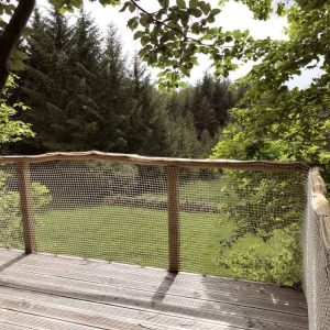 Cabane perchée dans les arbres, avec une vue dégagée sur la forêt verdoyante.